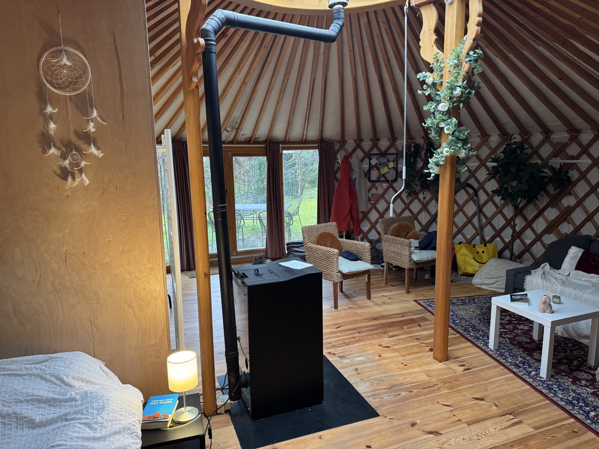 Inside the yurt: wood stove, lattice walls, wooden floor, wicker chairs